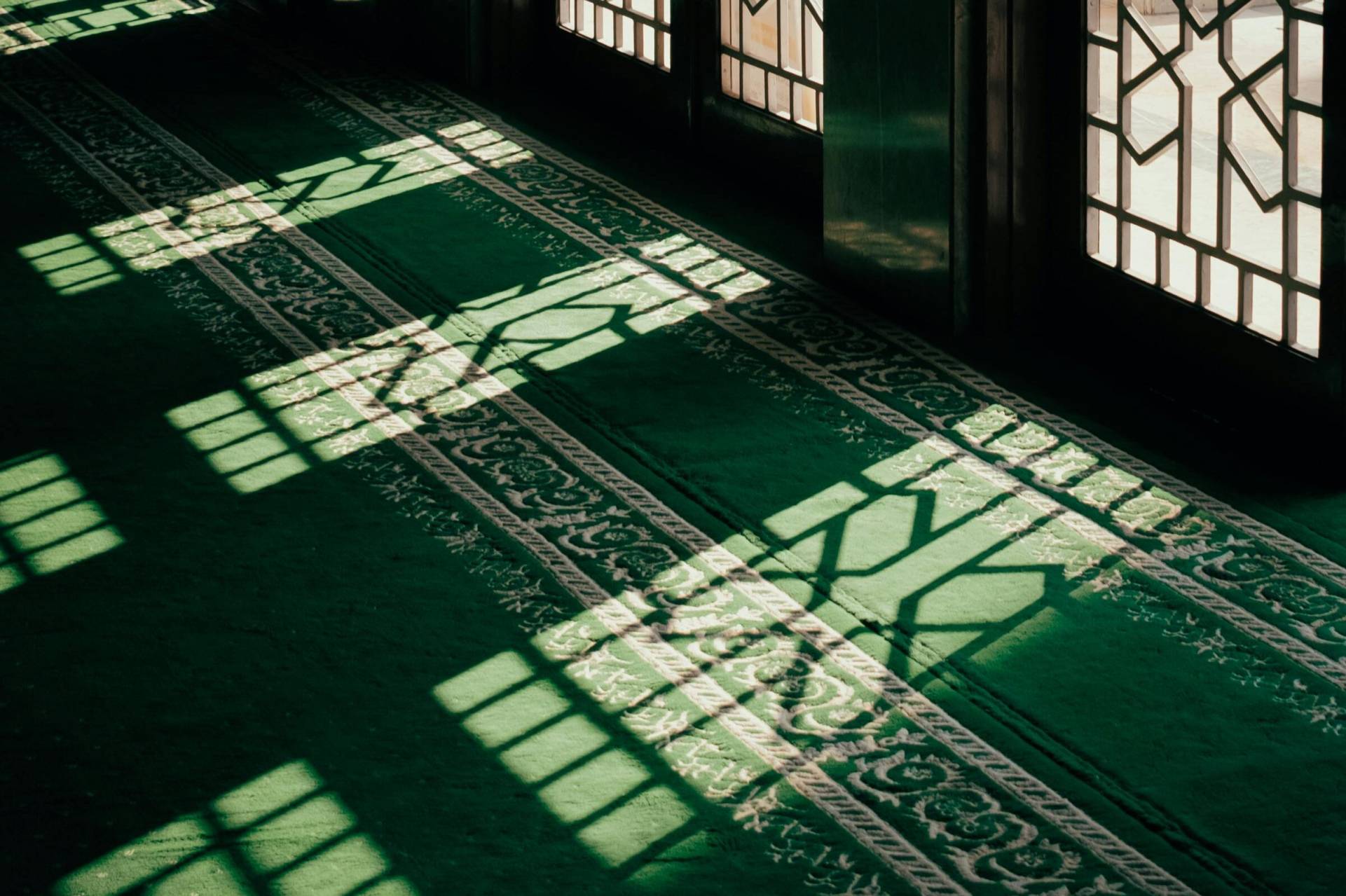 Gün ışığı vuran yeşil desenli cami halısı